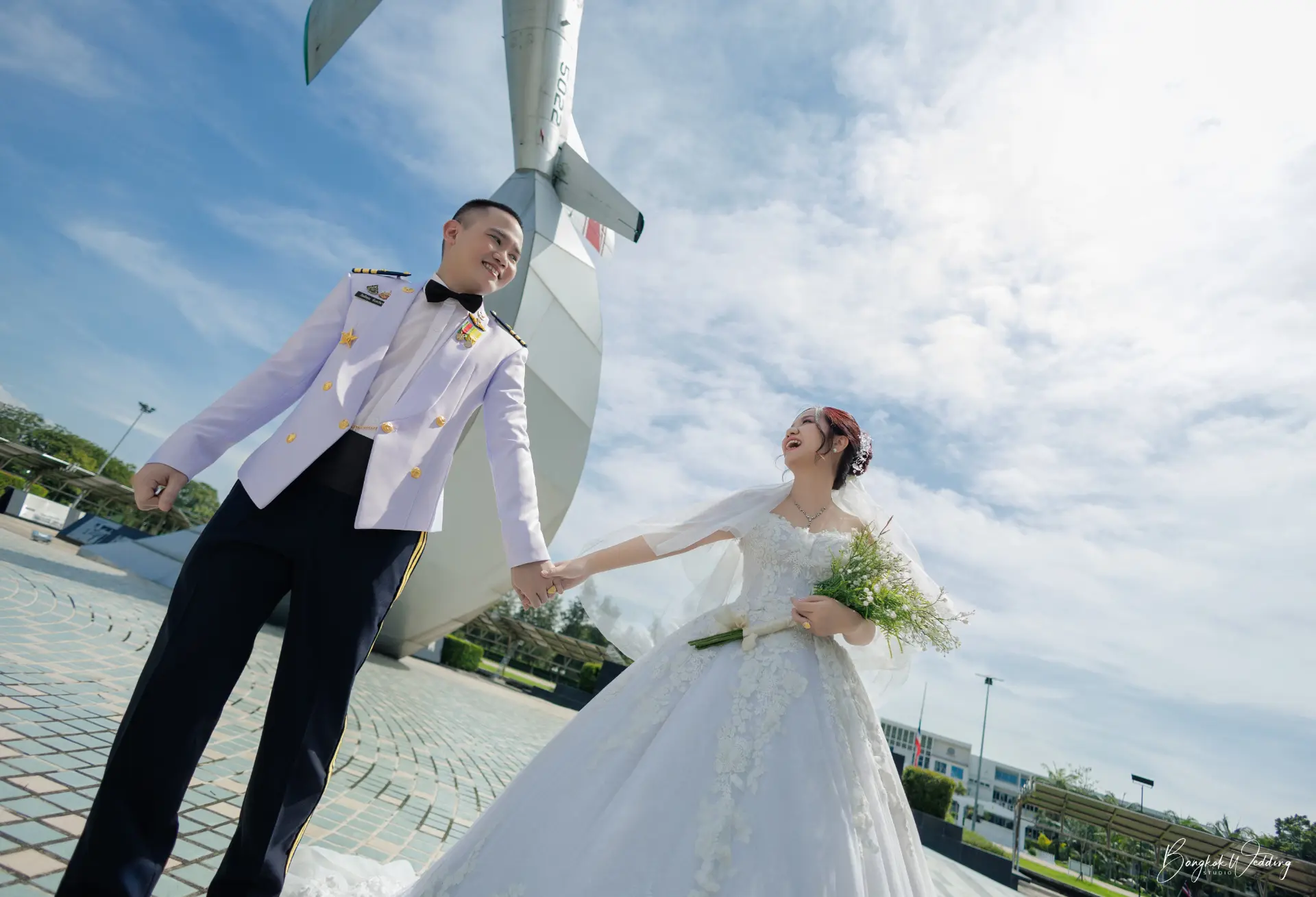 คู่รักยืนจับมือหน้าผืนฟ้ากว้างในอุทยานการบินกองทัพอากาศ